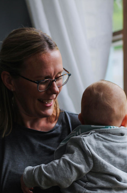 A mother smiling at her baby held in her arms